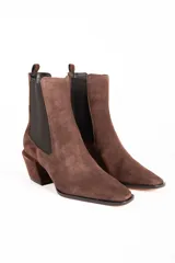 Bota tipo Chelsea de gamuza color marrón, con paneles laterales elásticos en color negro, puntera cuadrada y taco cuadrado de altura media.