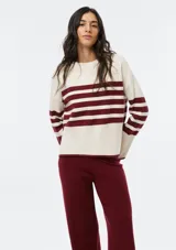 Buzo de tejido de punto con diseño de rayas horizontales en color bordeaux y crema, cuello redondo y mangas largas con puños acanalados.