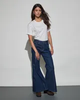 Jean de denim azul oscuro con diseño acampanado y costuras decorativas a contratono en las piernas.