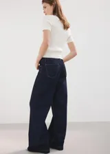 Jeans de corte ancho en color azul oscuro, con tiro medio y costuras pespunteadas en contraste.