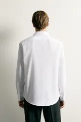 Camisa negra de corte regular fit, cuello italiano, manga larga con puño abotonado y cierre frontal con botones.