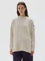 Buzo tejido de punto color beige, con cuello subido, diseño oversized y aberturas laterales en el ruedo.