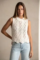 Top sin mangas de tejido de punto calado, color blanco, con cuello redondo acanalado y diseño de trenzas verticales. Presenta un ruedo con terminación festoneada.