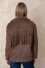 Chaqueta de gamuza sintética color marrón, con diseño de flecos en el pecho y la espalda. Presenta cierre frontal con botones, cuello camisero y bolsillos cuadrados frontales.