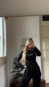 Remera de manga larga con cuello bote y mangas levemente acampanadas. Presenta un lazo integrado en la cintura que permite ajustar la prenda al cuerpo.
