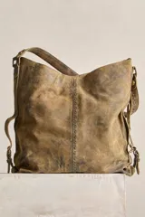 Cartera tote de cuero suave color marrón con efecto envejecido, cuerpo blando, caída relajada, correa ancha fija al hombro y costuras decorativas pespunteadas.