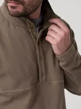 Buzo de polar para hombre en color otter, con cuello alto y cierre frontal parcial mediante botones a presión. Presenta mangas largas, bolsillos laterales y un diseño de corte recto con una costura horizontal decorativa en el pecho.