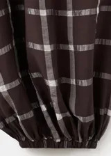Pantalón balloon de tiro medio en color marrón oscuro con estampa de cuadros. Cuenta con cintura ajustable con goma y cierre de lazo, además de dos bolsillos laterales y diseño abuchonado en los tobillos.