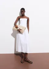 Vestido midi de corte evasé y escote palabra de honor. Presenta un diseño sin mangas con detalles fruncidos en los laterales y cierre de cremallera en la parte posterior.