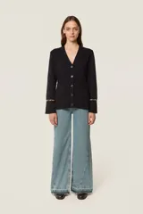 Cárdigan de punto color azul marino, con escote en V, cierre frontal con botones al tono y bolsillos de parche. Presenta mangas largas con aberturas decoradas con cuentas doradas en los puños.