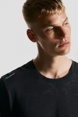 Remera deportiva negra de corte estándar y manga corta, con cuello redondo. Presenta un tejido funcional con tecnología DryMove™ y un sutil estampado jaspeado en tono más oscuro.