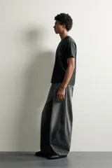 Jeans de denim de algodón color gris con efecto lavado, de corte relaxed barrel fit y tiro medio. Presenta diseño amplio con pinzas en las rodillas y costuras curvas, cierre frontal con botones y cinco bolsillos tradicionales.