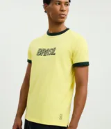 Remera de algodón color amarillo con cuello redondo y bordes de mangas en color verde oscuro. Presenta estampado frontal con la palabra Brasil en tipografía estilo retro.