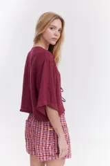 Blusa de lino italiano color beige, de manga corta, con escote en V y cierre frontal mediante lazos o moños.