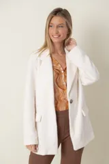 Blazer italiano color beige, de corte recto, con solapas de muesca, cierre de un botón y bolsillos simulados.