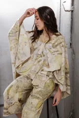 Vestido corto con estampado de hojas en tonos beige y amarillo, sin mangas y escote redondo. Incluye un poncho a juego con el mismo estampado.