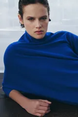 Jersey de lana en color azul vibrante, con cuello subido y diseño de manga murciélago con sisa ancha. Presenta puños ajustados y un corte holgado que se extiende hasta la cadera.