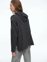 Buzo tejido de punto color negro, con capucha integrada, mangas largas y tajos laterales en el ruedo.