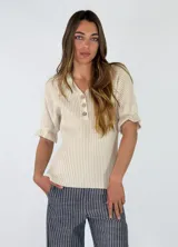 Top beige de punto en mezcla de algodón y poliéster, con diseño acanalado en el torso y mangas cortas de tejido calado con volados sutiles. Cuenta con escote en V y botonadura frontal con tres botones.
