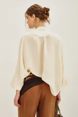 Camisa de viscosa color crema, con cuello mao y cierre frontal de botones. Presenta un delicado bordado floral en el frente y mangas tres cuartos con puños rectos.