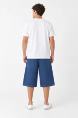Bermuda de denim color azul con efecto desgastado, corte holgado tipo baggy y largo por debajo de las rodillas.