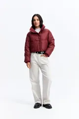 Campera puffer de corte cropped, color marrón oscuro, con cuello alto, cierre frontal con cremallera y botones a presión, y puños elásticos.