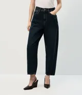 Pantalón de jean modelo new carrot, color azul oscuro, con tiro alto, cintura con pasantes, cierre frontal con botón y cremallera, bolsillos laterales y traseros, y detalles de tachas metálicas en forma de corazón.