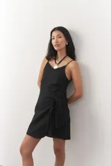 Vestido corto negro de lino, con breteles finos, escote en V y lazo lateral.