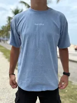 Remera oversize de color celeste melange, con diseño de estampado tipográfico en la espalda que incluye la frase "Time is Now" y otros detalles de colección.