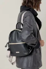 Mochila de cuero gamuzado color marrón con detalles en cuero metalizado plateado. Cuenta con cierre frontal, correas de cinta ajustables y placa metálica con logo de la marca en la parte inferior.