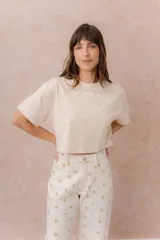 Remera crop color beige, de calce amplio, escote redondo y mangas cortas sueltas.