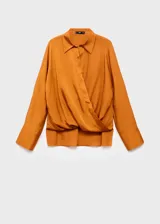 Camisa de tejido satinado en color mostaza, con diseño cruzado, cuello camisero, manga larga con puños abotonados y cierre delantero de botones ocultos.