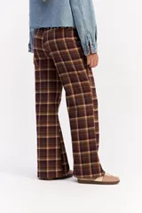 Pantalón de tiro medio con corte recto y leve apertura en el bajo. Presenta un diseño de estampado a cuadros en tonos beige y marrón.