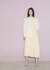 Vestido midi de punto fino con diseño plisado en la parte inferior y corte evasé. Presenta cuello halter, diseño sin mangas y una textura acanalada en el cuerpo.