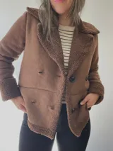 Chaqueta negra con forro tipo corderito, doble botonadura y cuello solapa.