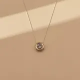 Collar con dije punto de luz, compuesto por una cadena de plata y un dije circular con borde en oro y centro de circonia.