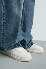 Zapatilla urbana monocolor blanca con cordones al tono, diseño de parte superior lisa, puntera redondeada y suela con volumen.