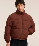 Campera marrón de poliamida con textura cuadriculada, corte boxy, cuello alto, cierre frontal con cremallera, bolsillos laterales y puños elásticos.