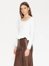 Top corto blanco de manga larga, ajustado al cuerpo, con escote cuadrado y un volante o peplum en el bajo.