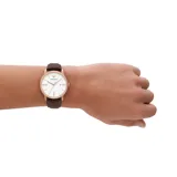 Reloj analógico Emporio Armani con caja de acero en tono oro rosa, esfera blanca con índices minimalistas y ventana de fecha, y correa de cuero marrón.