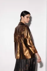 Chaqueta estilo blazer color marrón con flecos en la parte delantera y trasera, solapas y bolsillos frontales.