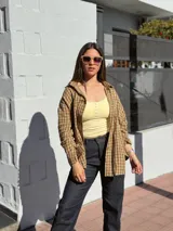 Camisa escocesa holgada, de manga larga, con estampa de cuadros en tonos de verde y marrón, y cierre frontal con botones.