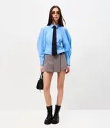Short pollera sastre de color gris, con diseño de plegado delantero, cintura estructurada y detalle de cinturón lateral con hebilla metálica.