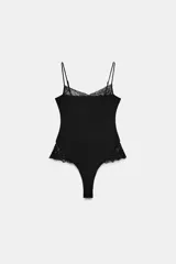 Body negro de corte cavado, con escote en V y tirantes finos ajustables. Presenta aplicación de encaje negro en el escote y en los laterales de la cadera.