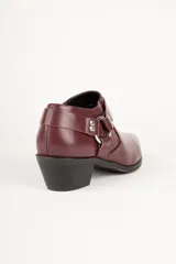 Botineta negra de cuero sintético con punta fina, taco bajo y apliques metálicos.