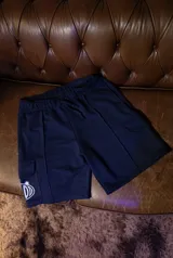 Short oversize color azul marino, con cintura elástica ajustable con cordón y bolsillos cargo en los laterales. Presenta un logo blanco en la parte inferior de uno de los bolsillos cargo.