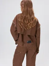 Campera de denim a rayas verticales con cuello de pana en color bordó. Presenta cierre frontal, mangas desmontables con cierre en los hombros, canesú en el pecho y bolsillos de parche cuadrados.