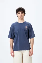 Remera negra de corte holgado con mangas cortas amplias y cuello redondo. Estampado pequeño de flor en el pecho y estampado grande en la espalda con diseño floral y texto.