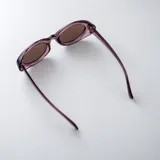 Lentes de sol con armazón ovalado de acetato traslúcido en tono gris oscuro y lentes oscuros.