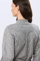 Camisa de algodón celeste con estampado floral pequeño, cuello mao, mangas largas con puños fruncidos y cierre frontal de botones.